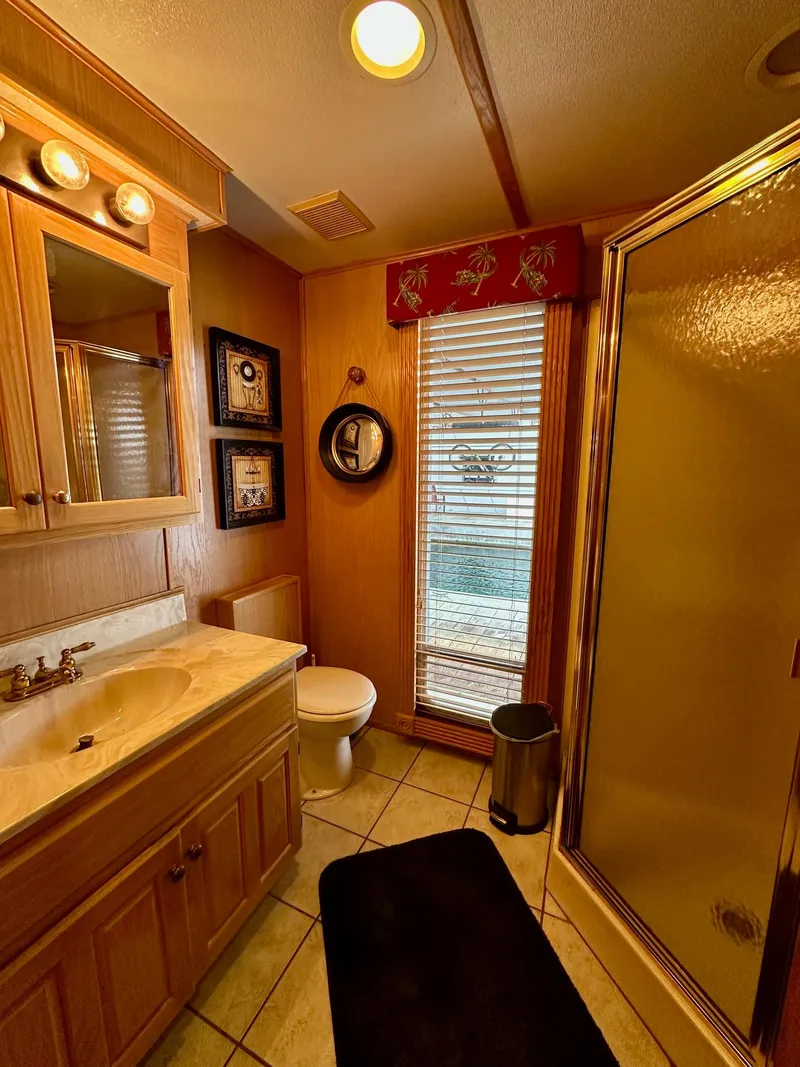 Slide: The Image of Compact bathroom in 2004 Lakeview 16x68 model with shower, vanity, and decorative accents. - 9