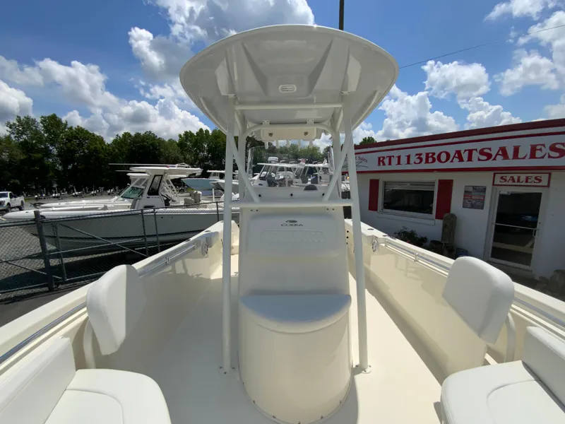 Slide: The Image of 2025 Cobia 220 Center Console boat at dealership, clear sky, and surrounding boats. - 22