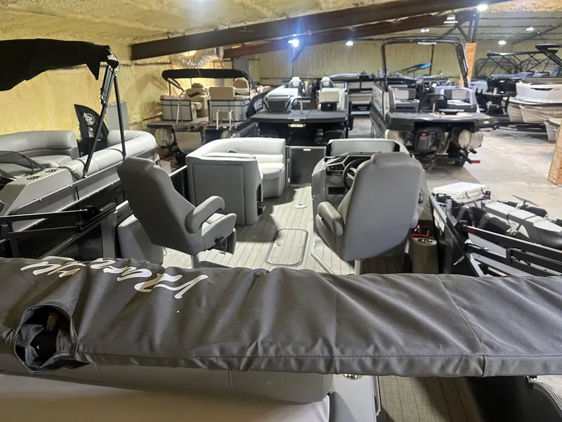 Slide: The Image of 2022 Manitou 23 Encore SL pontoon boat interior in showroom with multiple seating arrangements. - 2