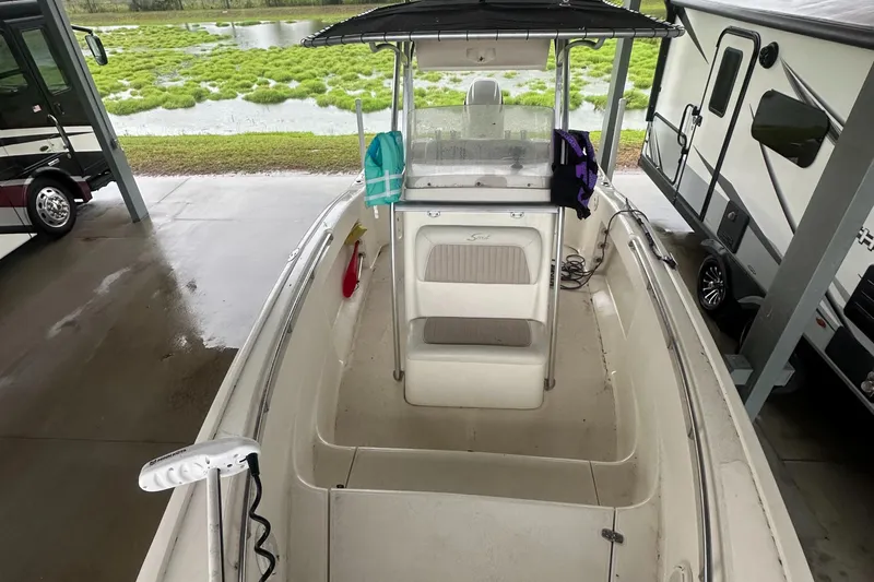 Slide: The Image of Scout 235 Sportfish boat with 2024 trailer, 2018 Suzuki 250 engine, parked under shelter. - 12