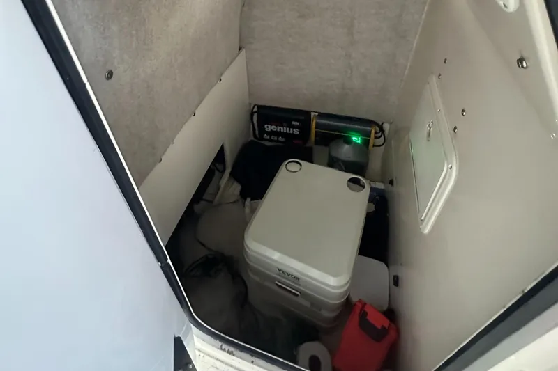 Slide: The Image of Storage compartment in a 2002 Scout 235 Sportfish boat, featuring a portable toilet and battery. - 14