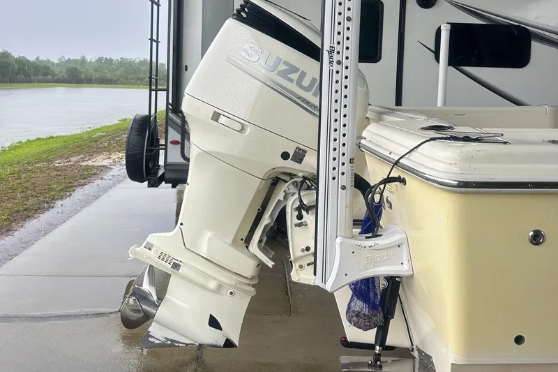 Slide: The Image of Scout 235 Sportfish with 2018 Suzuki 250 engine and 2024 trailer by a lake. - 8