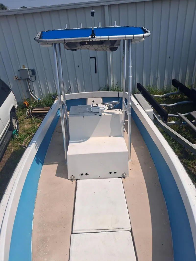 Slide: The Image of 1976 Shamrock Open Motorboat with blue canopy, docked near a metal building. - 6