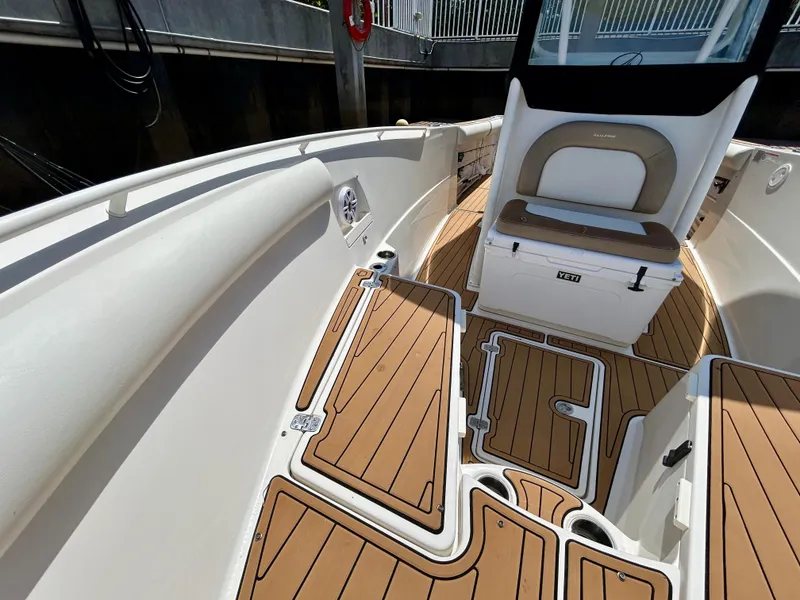 Slide: The Image of 2013 Sailfish 270 CC boat interior with cushioned seating and teak-style flooring. - 10