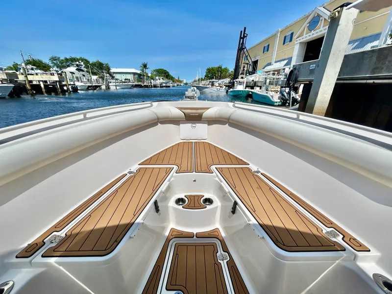 Slide: The Image of 2013 Sailfish 270 CC boat with teak deck, docked in a marina under clear blue skies. - 12