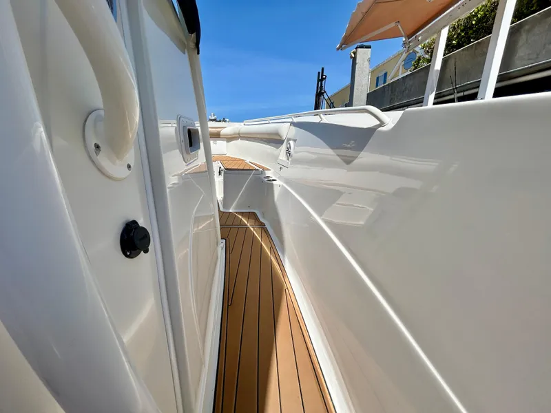 Slide: The Image of 2013 Sailfish 270 CC boat deck with sleek white finish and wooden flooring. - 18