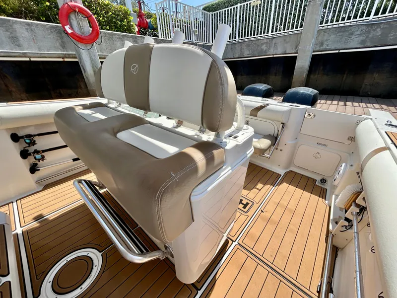 Slide: The Image of 2013 Sailfish 270 CC boat interior with tan and white seating, wooden deck, and safety equipment. - 22