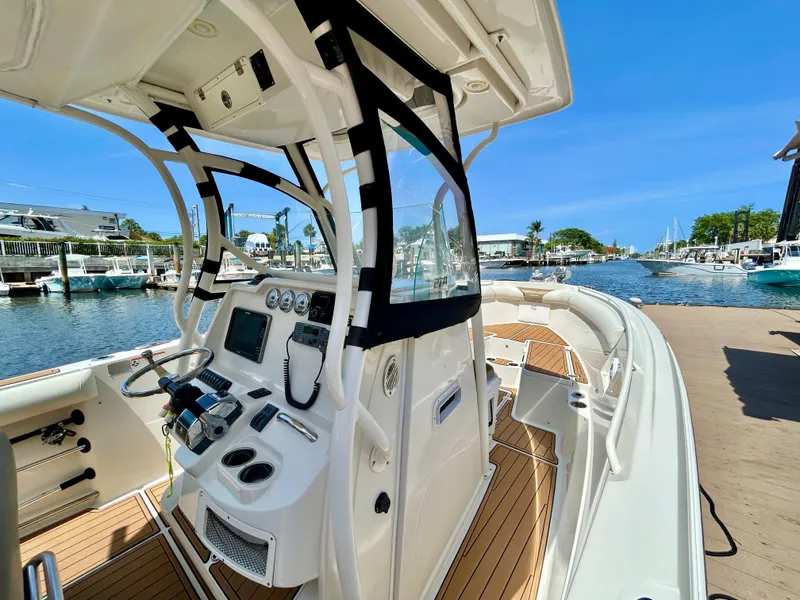 Slide: The Image of 2013 Sailfish 270 CC boat interior with helm, docked at marina under clear blue sky. - 24