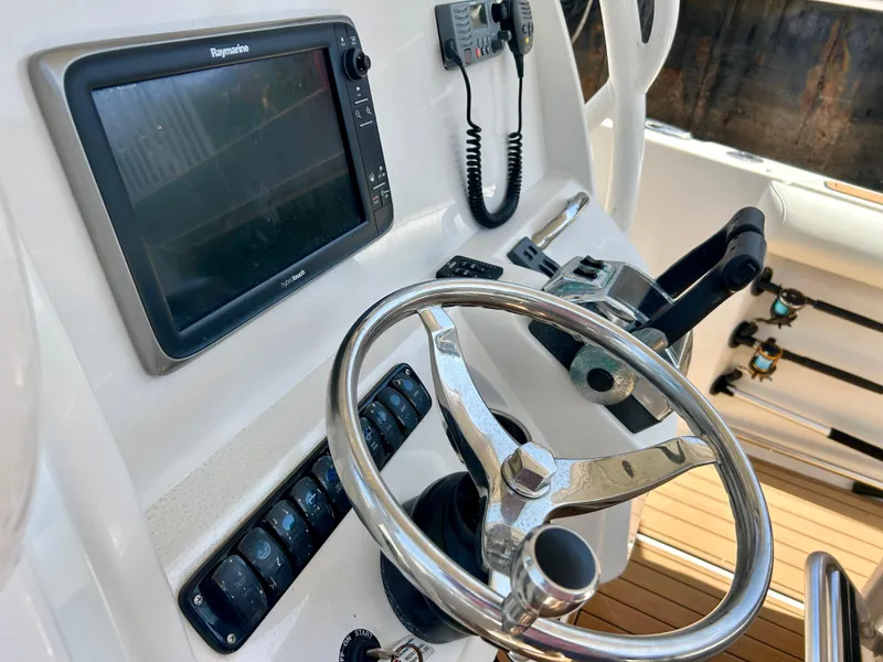 Slide: The Image of 2013 Sailfish 270 CC boat helm with steering wheel, navigation system, and control panel. - 26