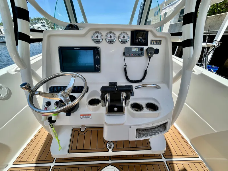 Slide: The Image of 2013 Sailfish 270 CC boat dashboard with steering wheel, controls, and navigation equipment. - 28