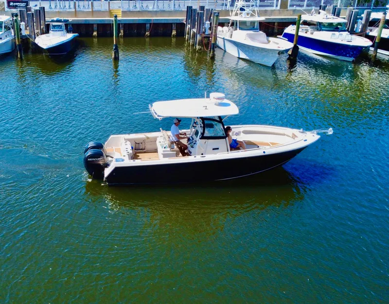 Slide: The Image of 2013 Sailfish 270 CC boat cruising in a marina with other boats docked nearby. - 3