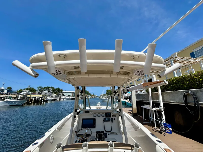 Slide: The Image of 2013 Sailfish 270 CC boat docked, featuring center console and rod holders under a clear blue sky. - 33