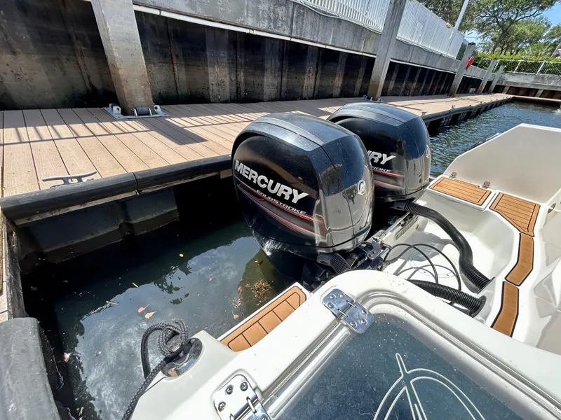Slide: The Image of Twin Mercury outboard engines on a 2013 Sailfish 270 CC boat docked by a wooden pier. - 45
