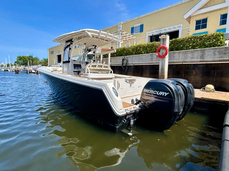 Slide: The Image of 2013 Sailfish 270 CC boat docked, featuring dual Mercury engines, sunny marina setting. - 5