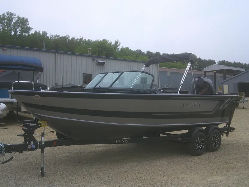 Slide: The Image of 2025 Lund 2075 Fisherman boat on trailer, parked outdoors near industrial building. - 4
