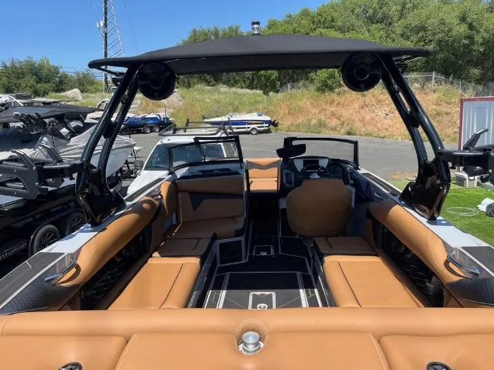 Slide: The Image of 2025 Supreme S240 boat interior with tan seating and black accents, docked outdoors. - 2