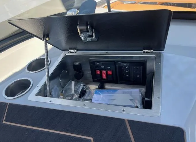 Slide: The Image of Open storage compartment on 2025 Supreme S240 boat with control panel and cup holders. - 22