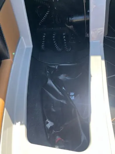 Slide: The Image of Interior view of a 2025 Supreme S240 boat, featuring storage compartment and coiled cables. - 33