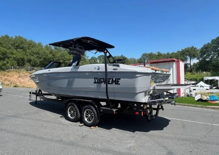 Slide: The Image of 2025 Supreme S240 boat on trailer, parked outdoors under clear blue sky. - 40