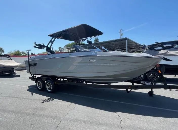 Slide: The Image of 2025 Supreme S240 boat on trailer under clear blue sky. - 41