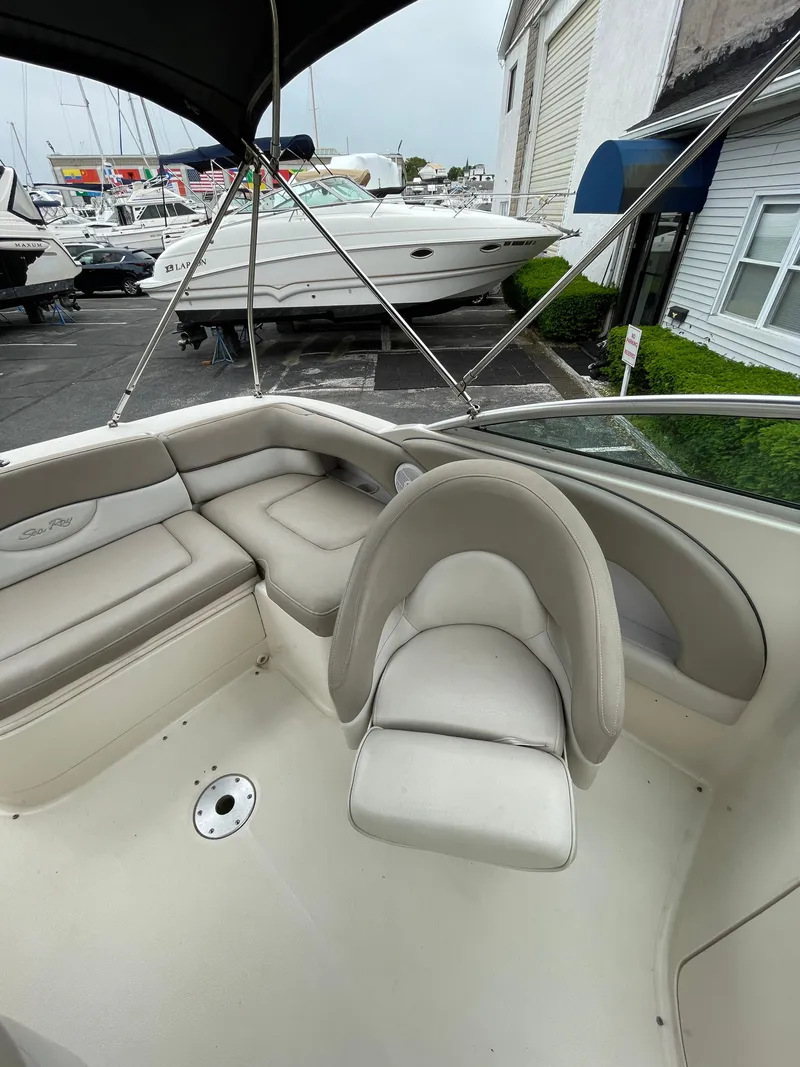 Slide: The Image of 2004 Sea Ray 220 Sundeck boat interior with beige seating and canopy, docked at marina. - 14
