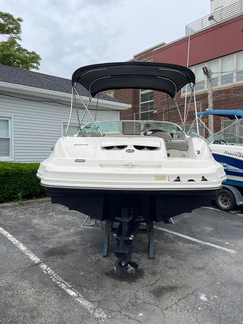 Slide: The Image of 2004 Sea Ray 220 Sundeck boat with canopy, parked on a trailer in a lot. - 19