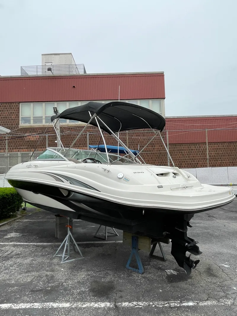 Slide: The Image of 2004 Sea Ray 220 Sundeck boat on stands, with canopy, in a parking lot. - 20