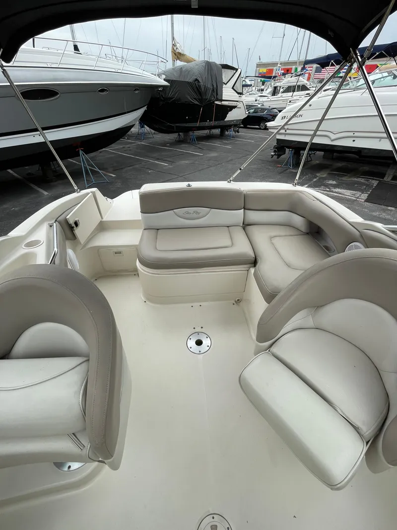 Slide: The Image of 2004 Sea Ray 220 Sundeck boat interior with beige seating, docked among other boats. - 23