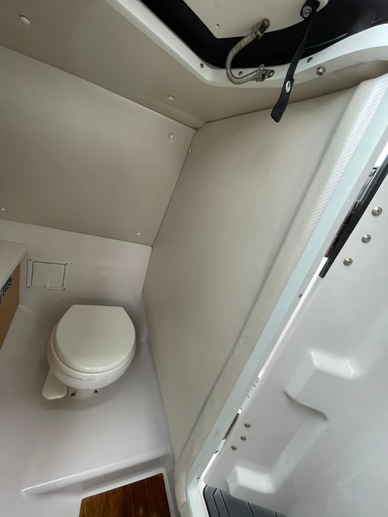 Slide: The Image of 2004 Sea Ray 220 Sundeck interior with compact marine toilet and storage space. - 29