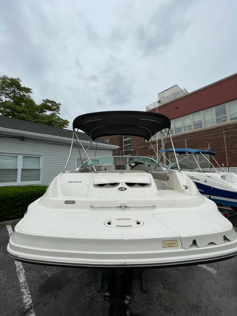 Slide: The Image of 2004 Sea Ray 220 Sundeck boat with canopy, parked outdoors on a cloudy day. - 3