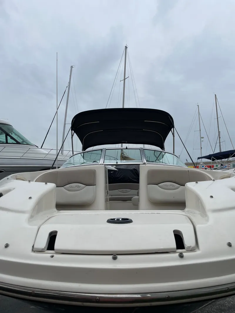 Slide: The Image of 2004 Sea Ray 220 Sundeck boat with canopy, docked at marina under cloudy sky. - 5