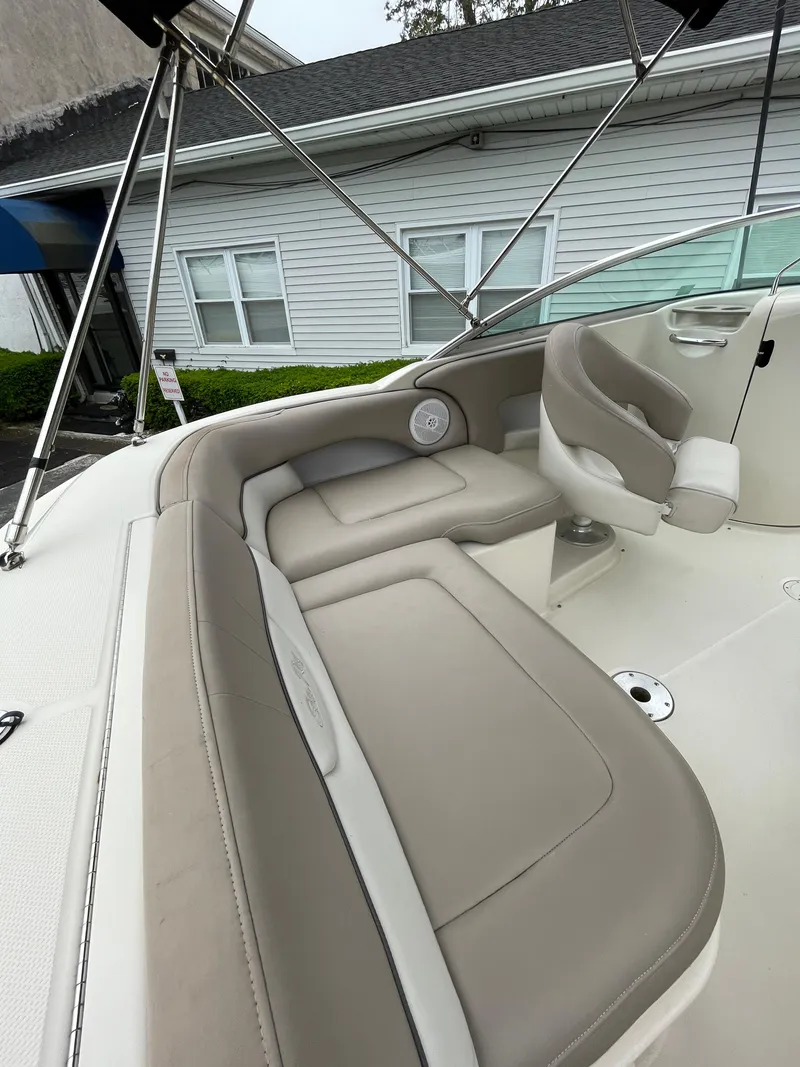 Slide: The Image of 2004 Sea Ray 220 Sundeck interior with beige seating and steering area. - 9