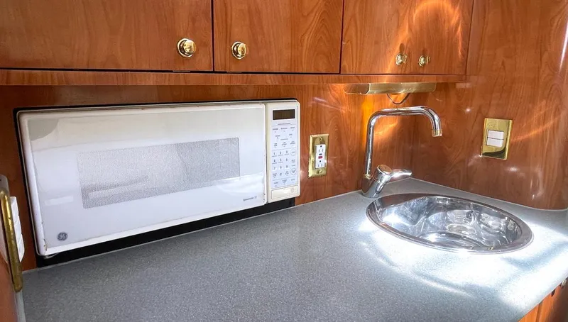 Slide: The Image of 2002 Fountain 38 Express Cruiser kitchen with microwave, sink, and wooden cabinetry. - 13