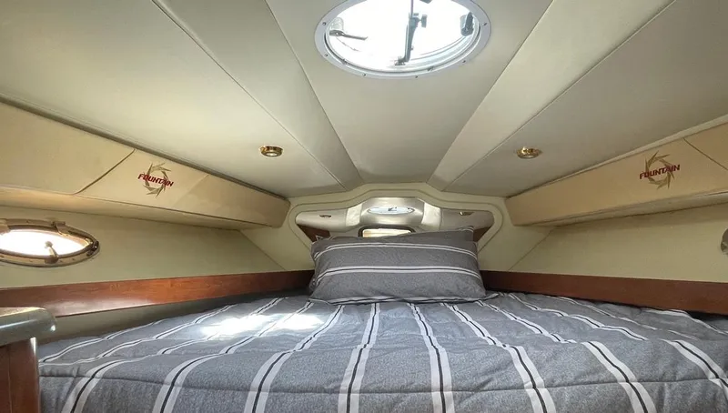 Slide: The Image of 2002 Fountain 38 Express Cruiser cabin with striped bedding and overhead hatch. - 15