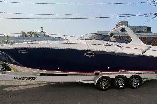 Slide: The Image of 2002 Fountain 38 Express Cruiser on trailer, sleek design, navy hull, white accents. - 2