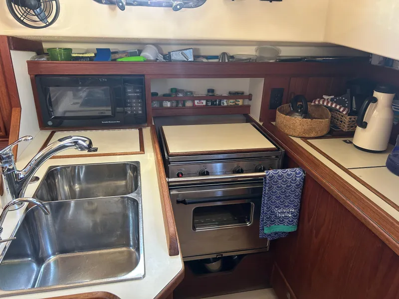 Slide: The Image of Compact galley kitchen in a 1998 Island Packet 350 sailboat with sink, stove, and microwave. - 29