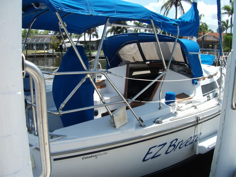 Slide: The Image of 1992 Catalina 30 MkII sailboat with blue canopy docked in a marina. - 30