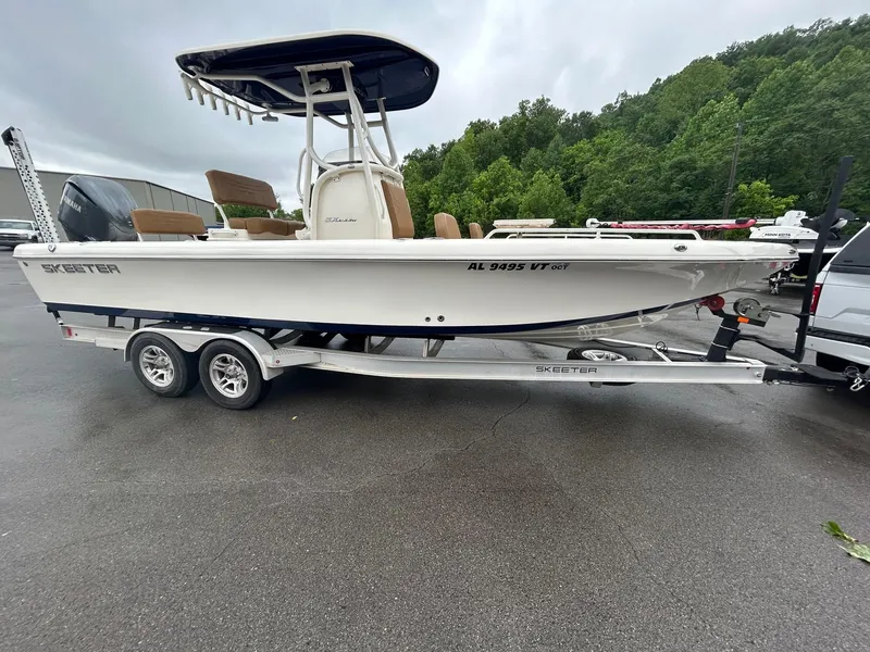 Slide: The Image of 2023 Skeeter SX 2250 boat on trailer, parked outdoors, with lush green trees in background. - 1