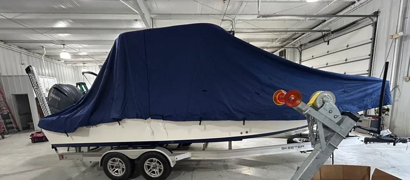 Slide: The Image of 2023 Skeeter SX 2250 boat covered in blue tarp on trailer in garage. - 15