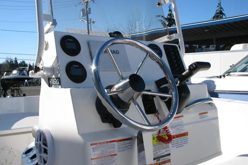 Slide: The Image of 2026 Robalo R160 Center Console boat steering wheel and dashboard controls. - 34