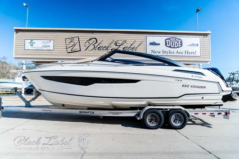 Slide: The Image of 2023 Hussar 850 boat on trailer, displayed outdoors near Black Label store. - 10