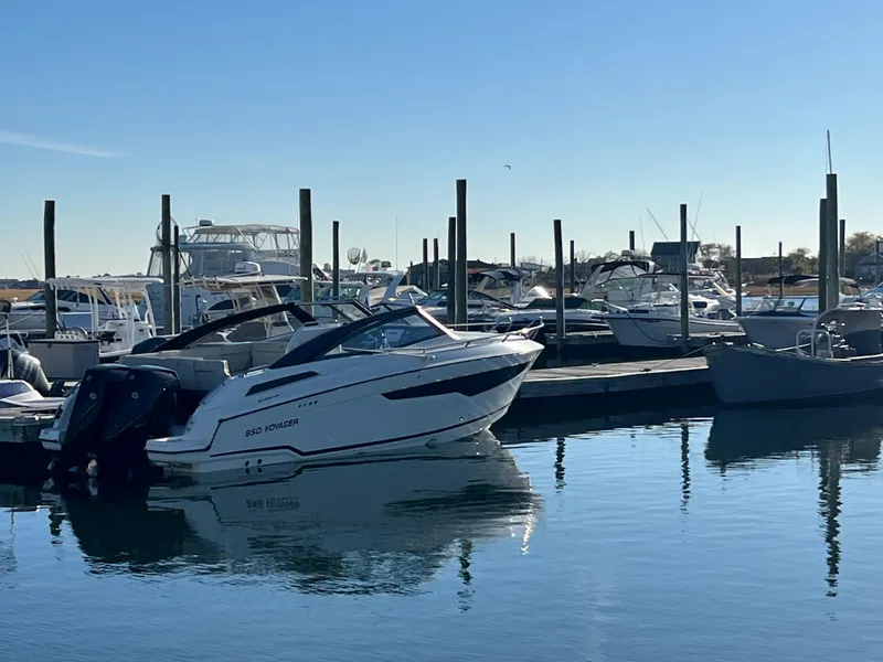 Slide: The Image of 2023 Hussar 850 boat docked in a marina under clear blue skies. - 2