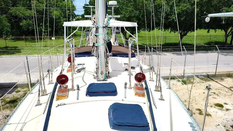 Slide: The Image of 1985 Tayana Vancover 42 sailboat deck with rigging and equipment, surrounded by greenery. - 12