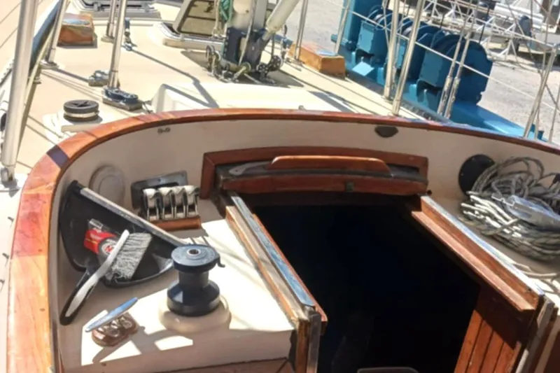Slide: The Image of 1985 Tayana Vancover 42 sailboat cockpit with winch, ropes, and wooden hatch. - 15