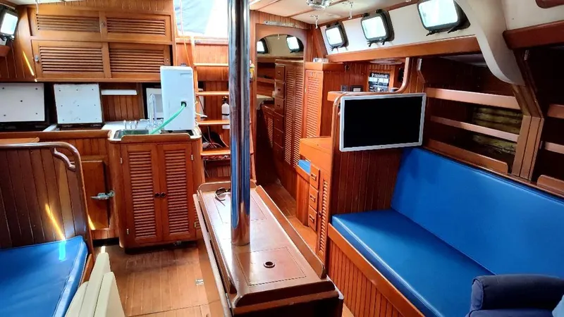 Slide: The Image of Interior of 1985 Tayana Vancover 42 sailboat with wood paneling and blue seating. - 30
