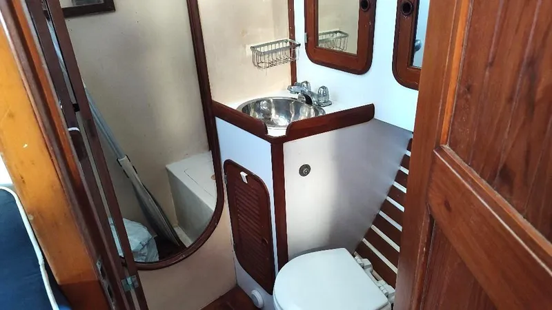 Slide: The Image of 1985 Tayana Vancover 42 yacht bathroom with wooden accents, sink, and toilet. - 35