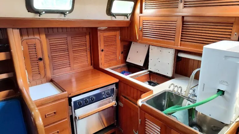 Slide: The Image of 1985 Tayana Vancover 42 yacht kitchen with wooden cabinetry and stainless steel appliances. - 40
