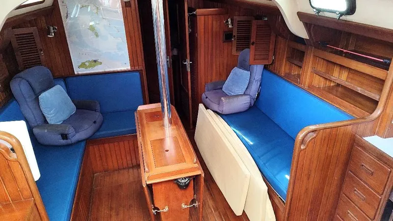 Slide: The Image of Interior of 1985 Tayana Vancouver 42 sailboat with blue seating and wooden finish. - 42