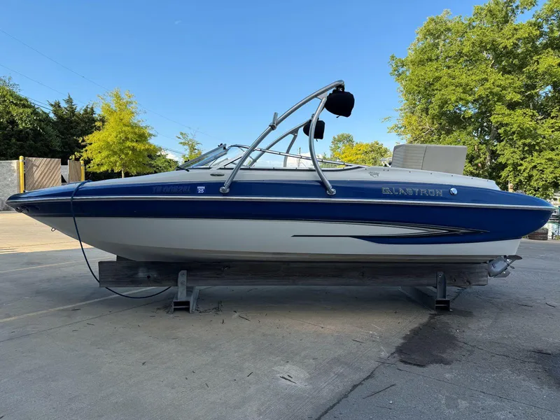 The Image of 2006 Glastron GX 235 boat on trailer, blue and white, parked outdoors. - 0