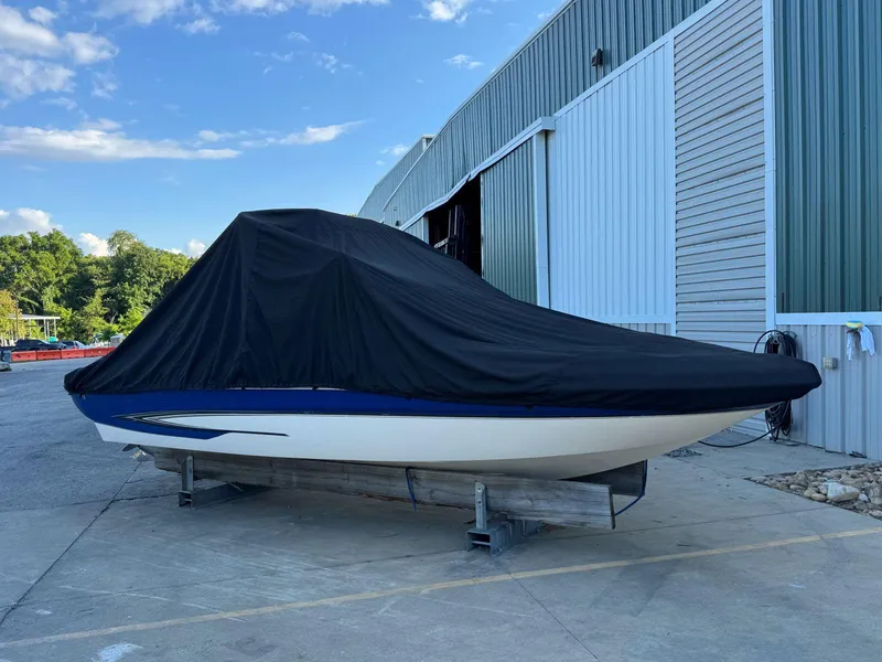 Slide: The Image of 2006 Glastron GX 235 boat covered, parked outside a metal building. - 15